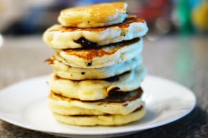 A stack of seven fluffy pancakes with chocolate chips. The background is blurred out.