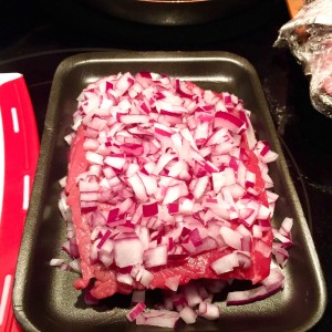 Chaliapin Steak preparation shot with raw onions on steak