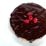 An overhead shot of a Chocolate-Covered Raspberry Cheesecake with a white background.
