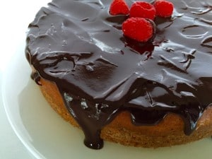 A close-up of chocolate ganache dripping off the sides of a Chocolate-Covered Raspberry Cheesecake