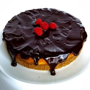 A ¾ shot of Chocolate-Covered Raspberry Cheesecake with chocolate ganache dripping from the side.