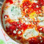 A close-up photo of shakshuka in a skillet. The various colours and textures are apparent.
