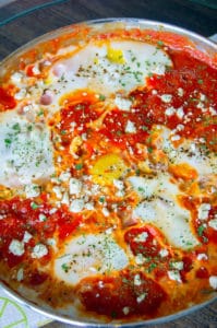 A highly textured photo of shakshuka cooked in a skillet.
