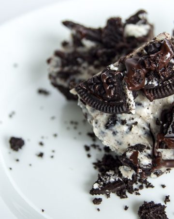 A No Bake Oreo Cheesecake Bars propped up by other bars.