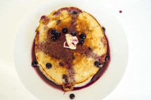 An overhead photo of blueberry buttermilk pancakes on a white plate.