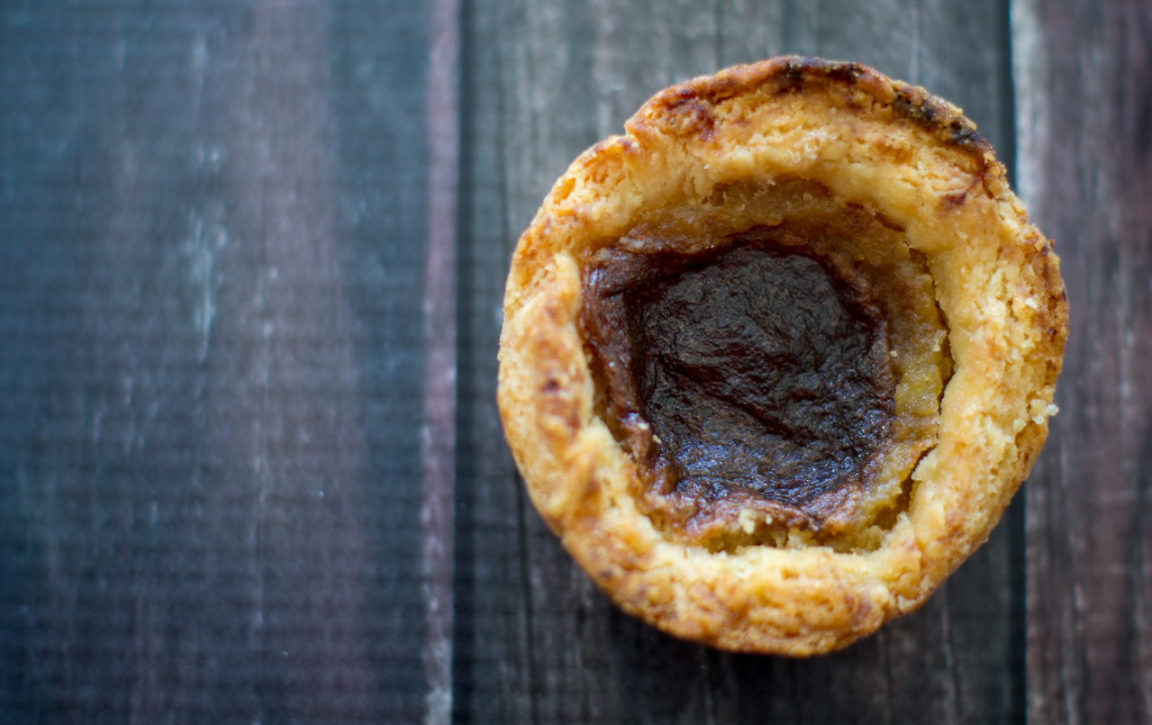 A photo of a single butter tart, positioned slightly left of centre.