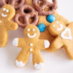 Three smiling gingerbread men propped up by other gingerbread cookies for Christmas.