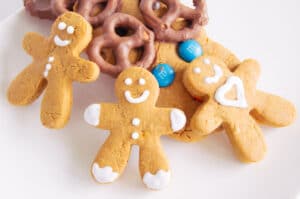 Three smiling gingerbread men propped up by other gingerbread cookies for Christmas.