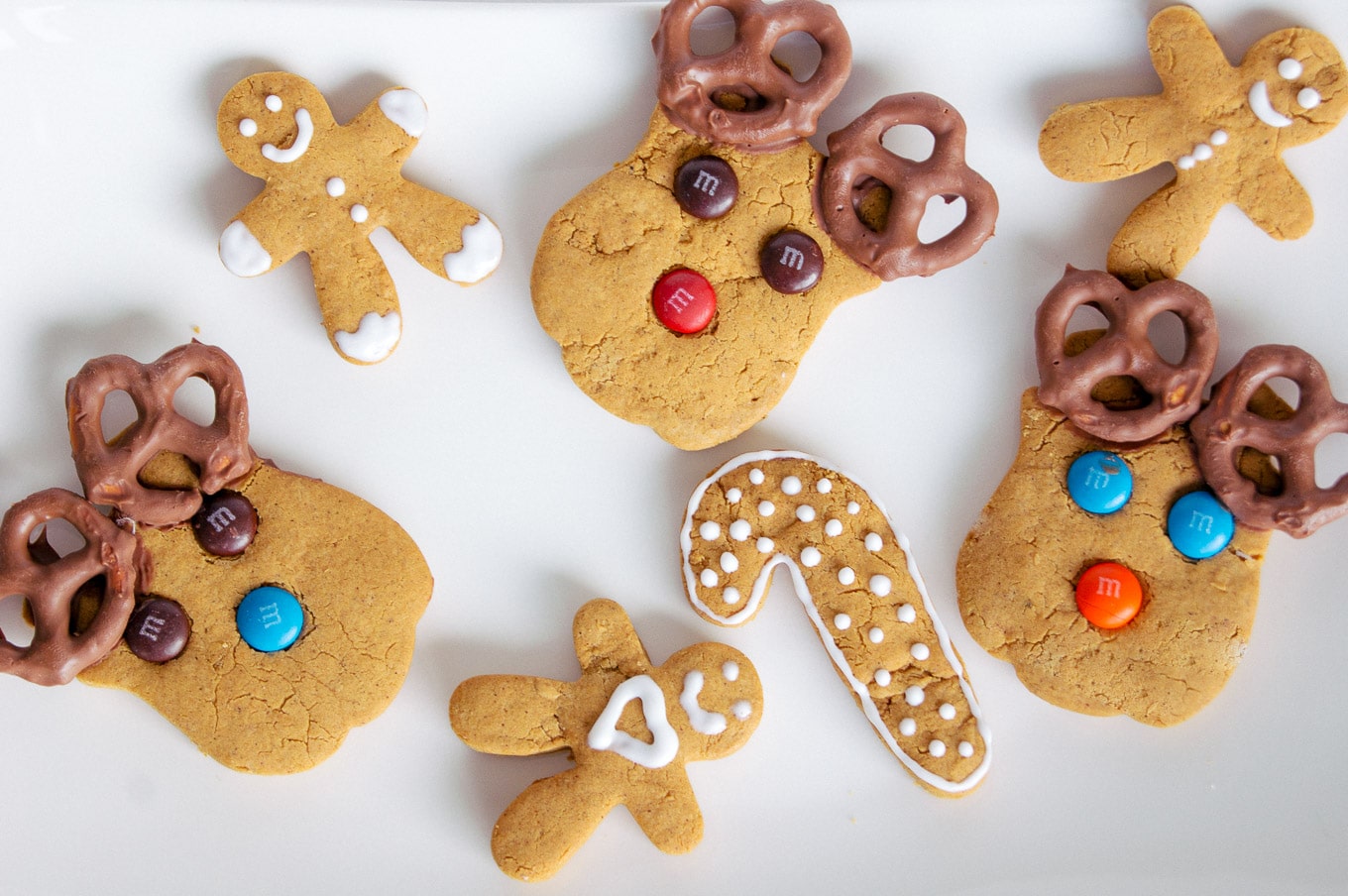 A photo of various gingerbread cookies for Christmas, including some of gingerbread moose with smarties for their eyes and nose, and chocolate-covered pretzels for antlers.
