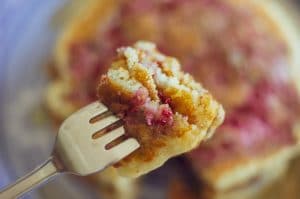 A close-up photo of of Raspberry Swirl Pancakes on fork, ready to be eaten with the blurred stack in the background.