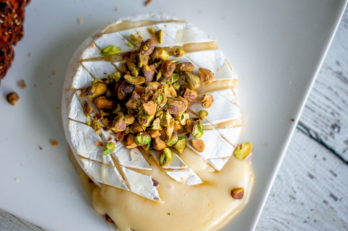 An overhead shot of Baked Brie with pistachios prior to having honey drizzled over.