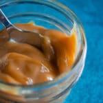 A close-up of dulce de leche made using condensed milk on a blue background.