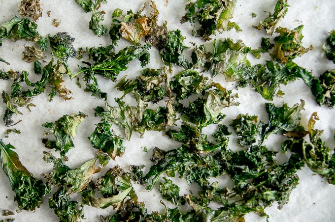 A top down view of baked kale chips on a baking tray.