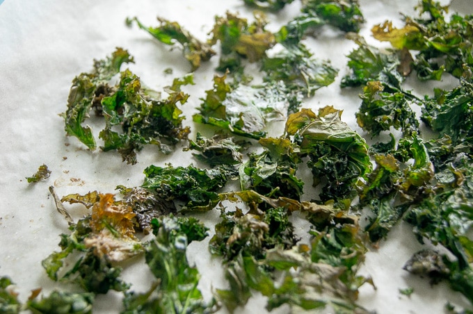 An image of baked kale chips on parchment paper.