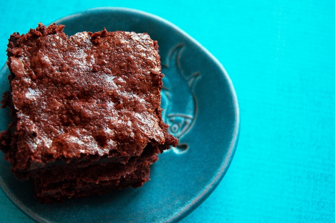 An overhead shot with a plate of homemade olive oil brownies on the left and a blue background.