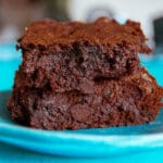 A closeup shot of fudgy Olive Oil Brownies stacked atop one another.