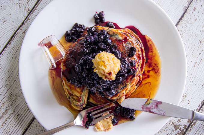 An overhead photo of the pancakes showing off the brown sugar butter atop the stack of blackberry pancakes.
