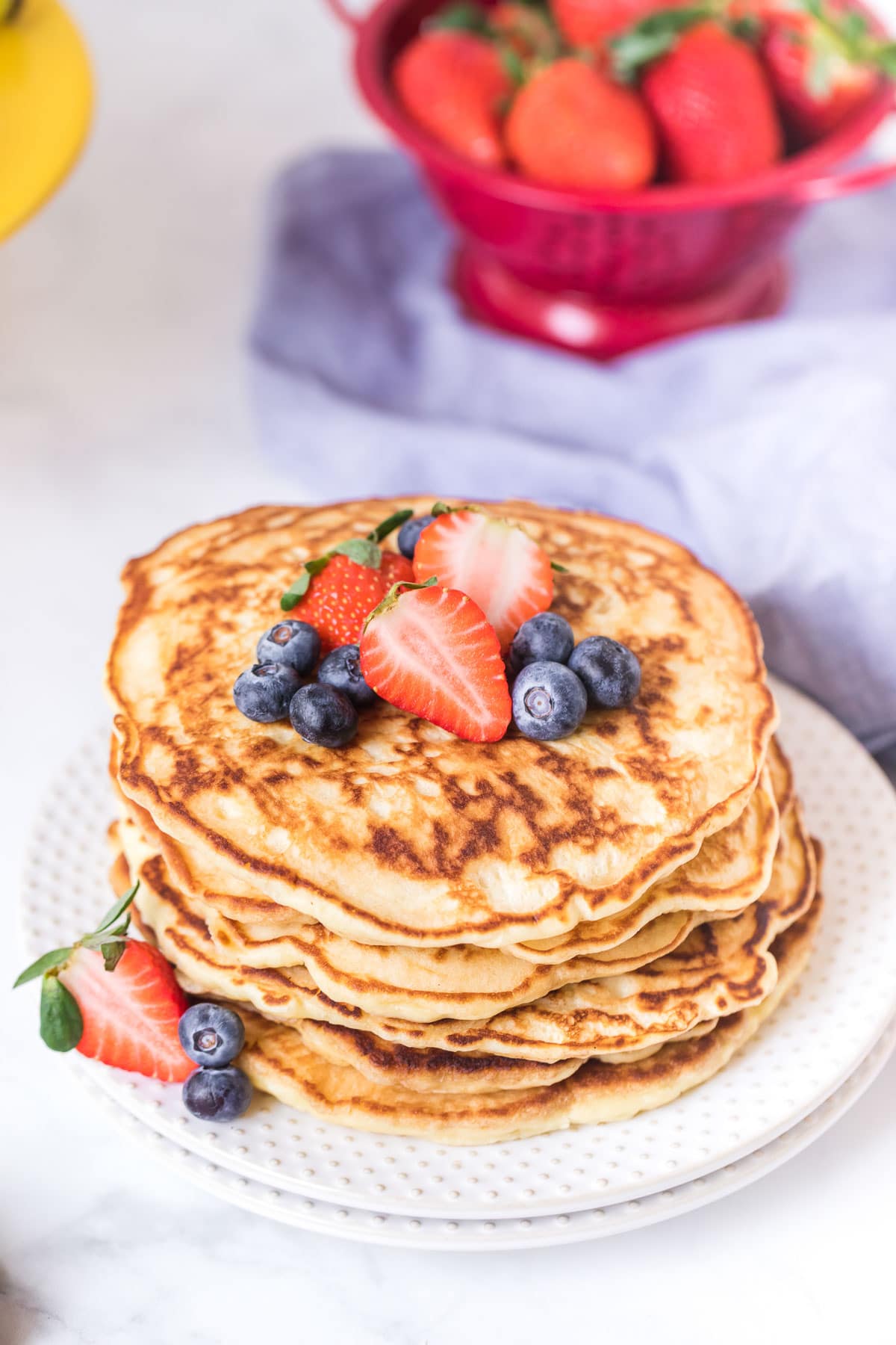 A simple stack of pancakes decorated with strawberries and blueberries.