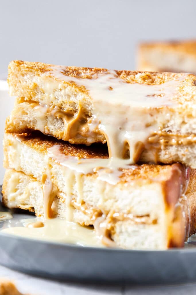 A close-up photo showing condensed milk oozing down the side of two Hong Kong style French Toast sandwiches.