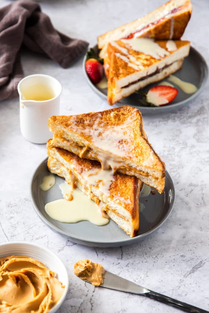 Two french toast sandwiches, stuffed with peanut butter, on a grey plate