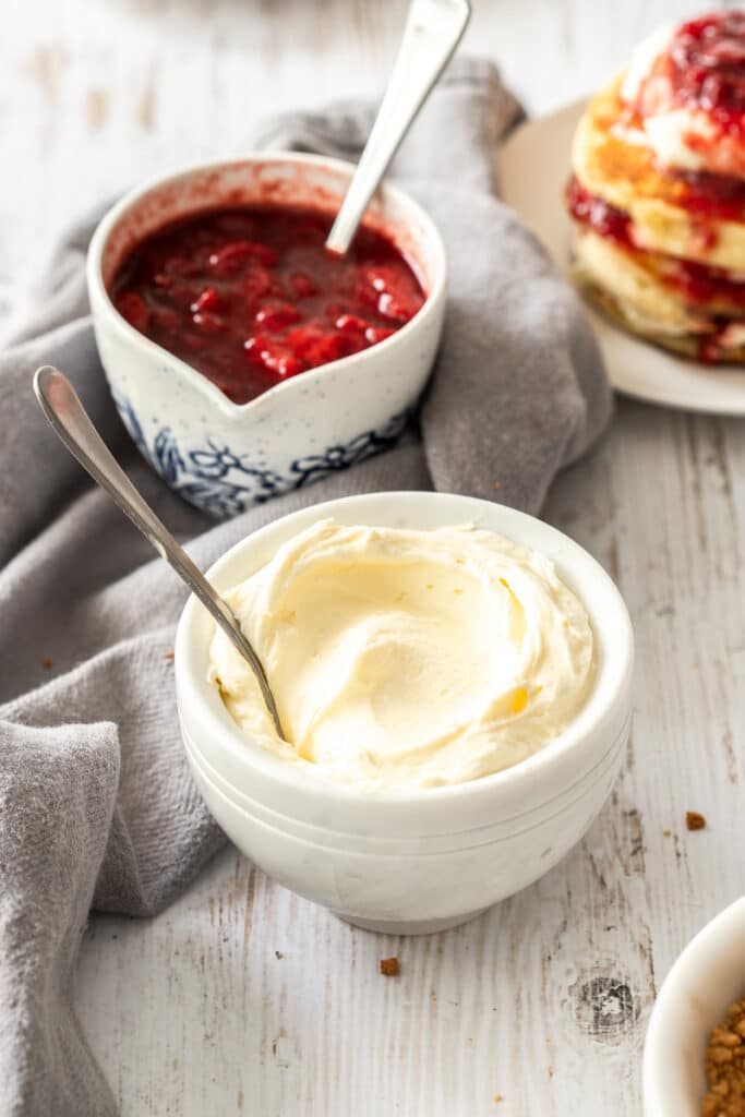 Two bowls of strawberry sauce, and whipped cheesecake.