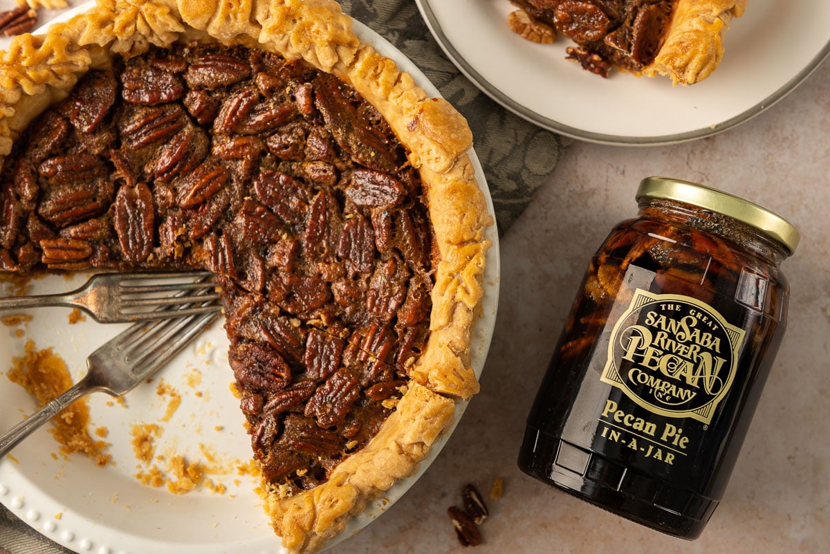 Unopened jar of William Sonoma's pecan pie filling next to a pie missing a large slice.