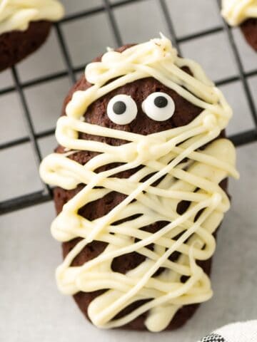 A close-up of a chocolate madeleine decorated to look like a mummy for Halloween.