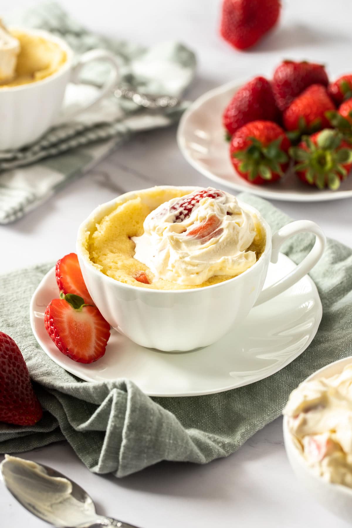Strawberry shortcake mug cake, decorated with a dollop of strawberry whipped cream,.