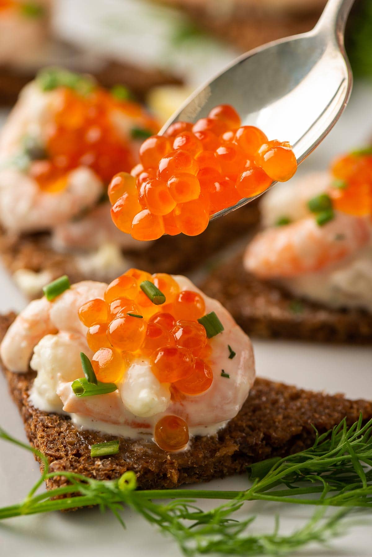Bright orange roe being spooned on to a slice of Swedish Toast Skagen.