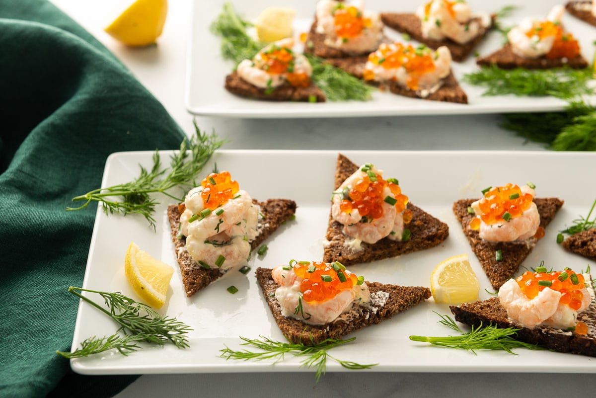 Two white rectangular platters serving Swedish toast cut into triangles.