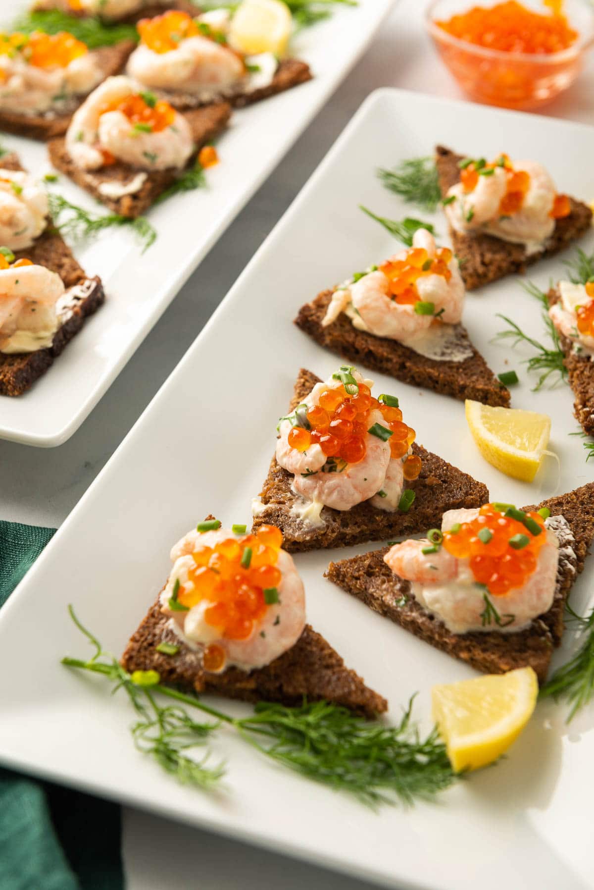 A platter of toast skagen triangles decorated with dill and lemon.