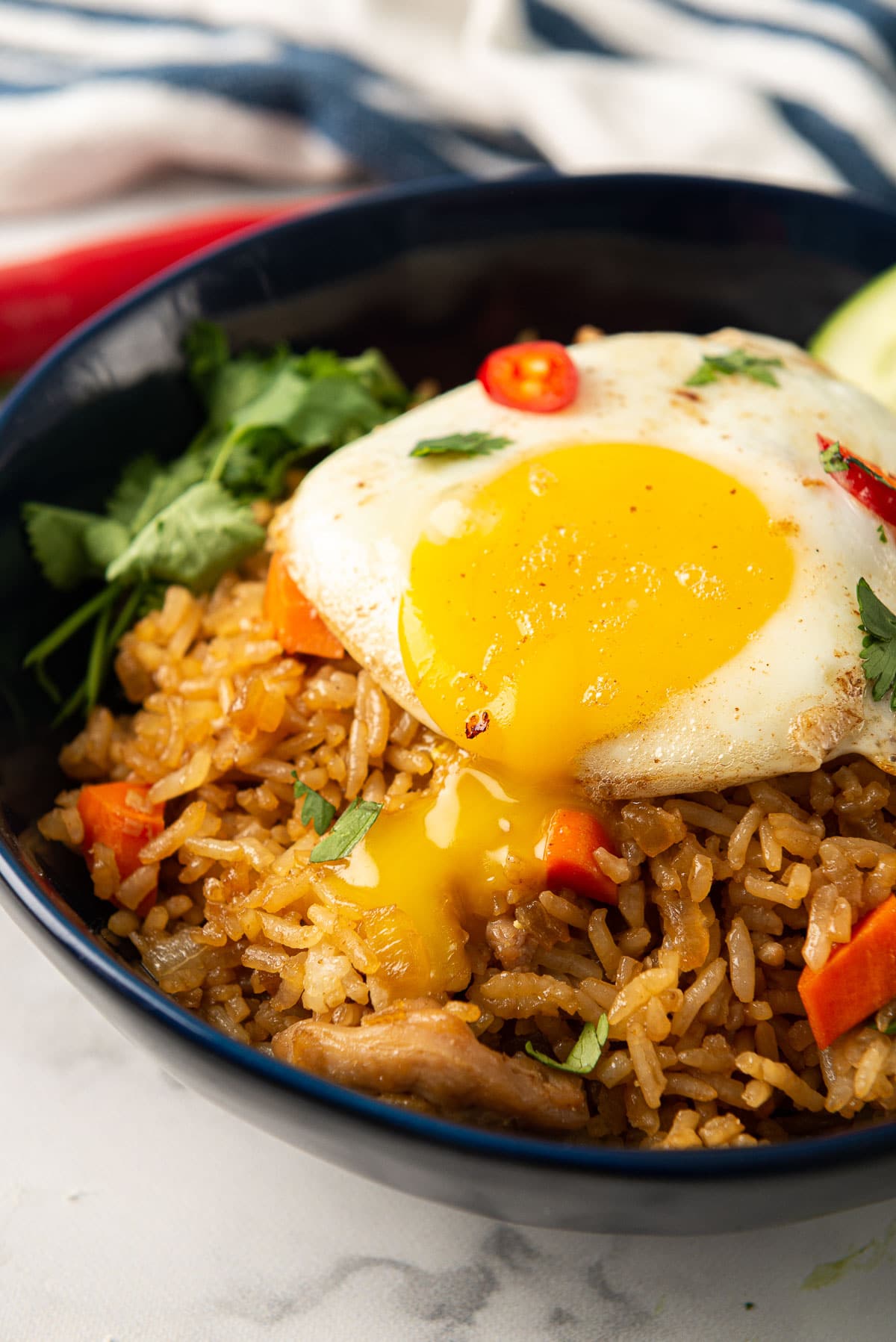 Indonesian fried rice with a fried egg on top - the yolk has been popped and is oozing into the rice.
