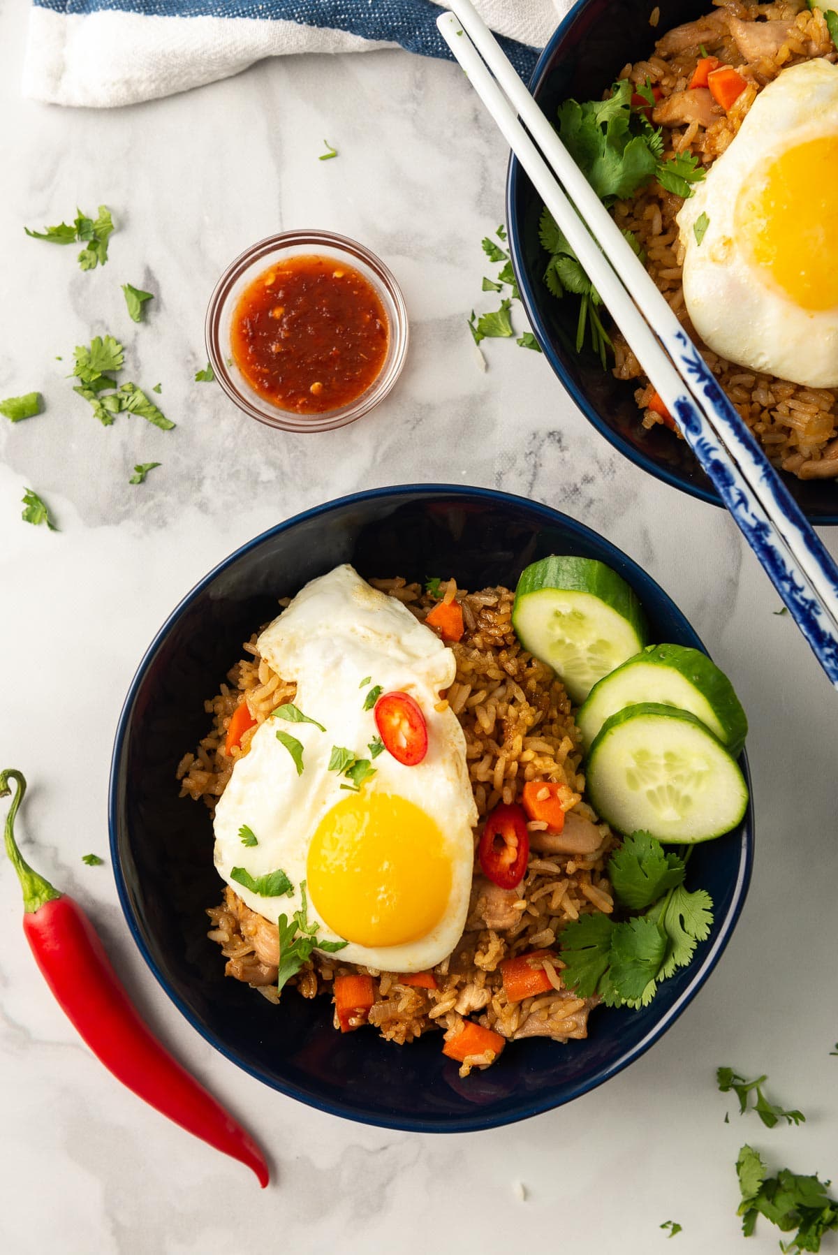 A top down photo of two blue bowls of Indonesian nasi goreng.
