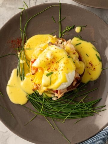 An overhead shot of Lobster Benedict on a grey plate, the egg has been popped.