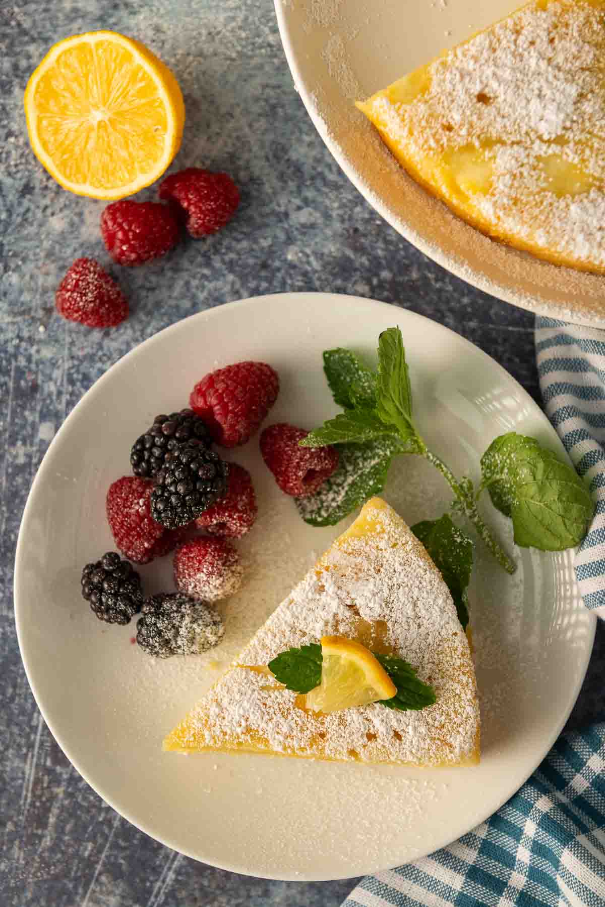 A slice of lemon ricotta cake with berries on a white plate.