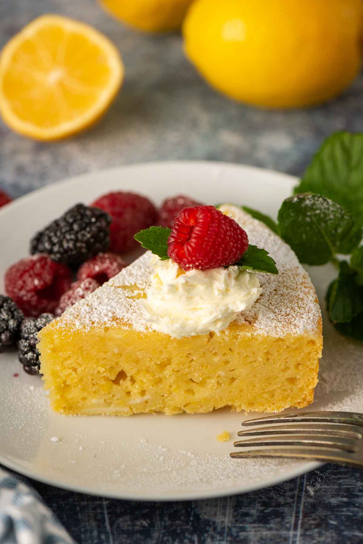 A ¾ view of a slice of Italian cake made with lemon and ricotta with a bit of mascarpone on top.
