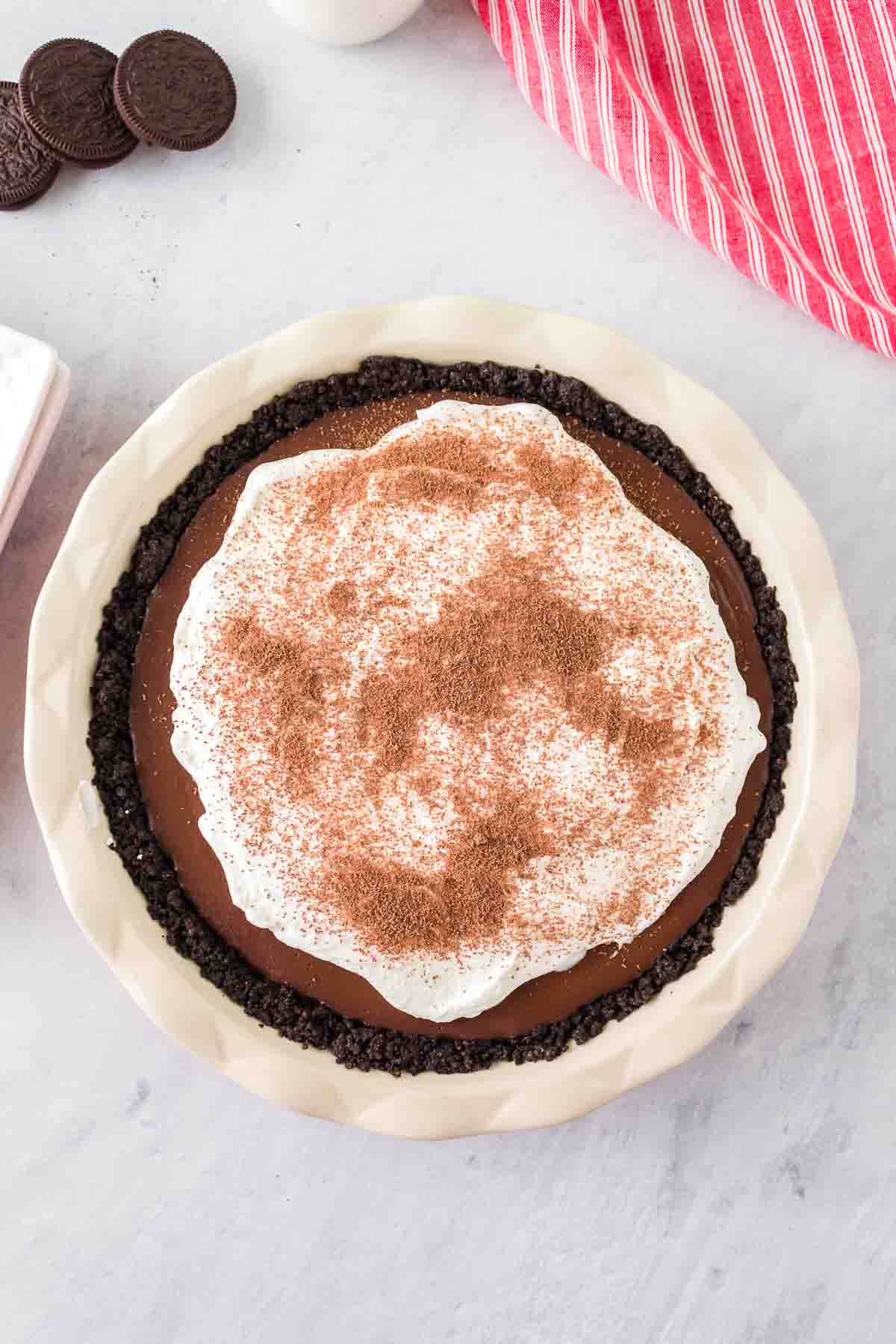 A top down photo of chocolate cream pie with an Oreo crust in a white pie dish.