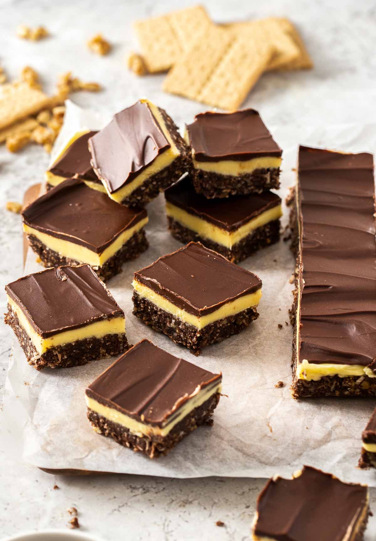Several Nanaimo bars on parchment paper.
