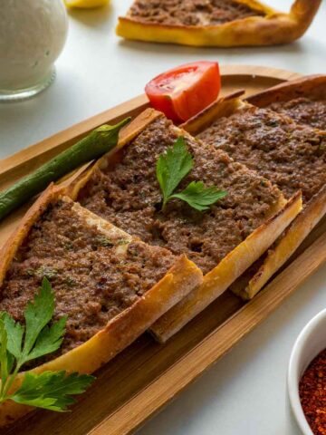 Turkish pide with ground beef on a wooden platter.
