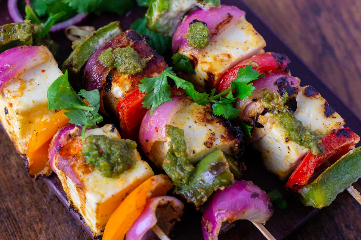 Three skewers of paneer tikka with bell peppers and onions.