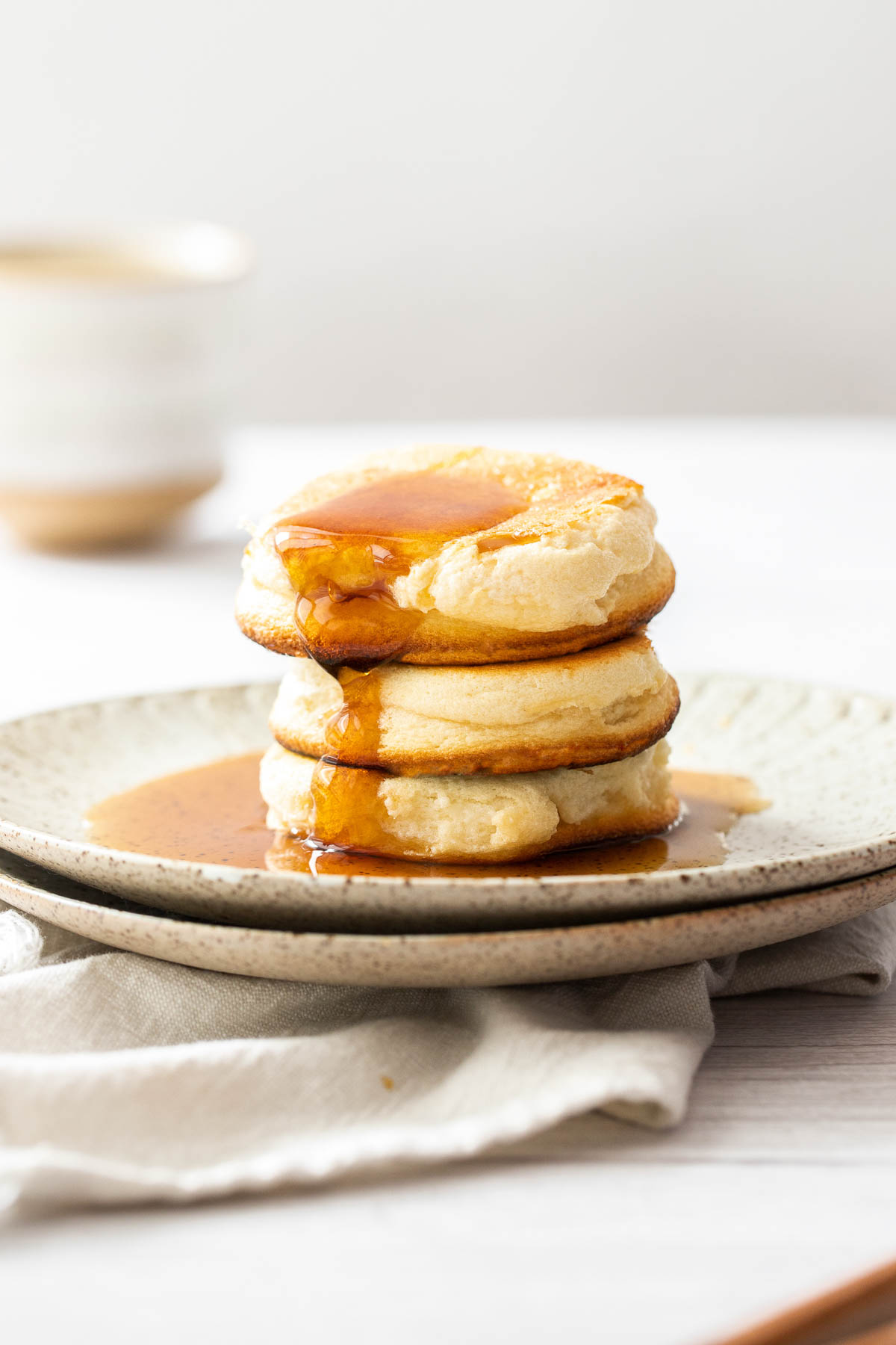 A stack of fluffy japanese souffle pancakes with maple syrup on top.