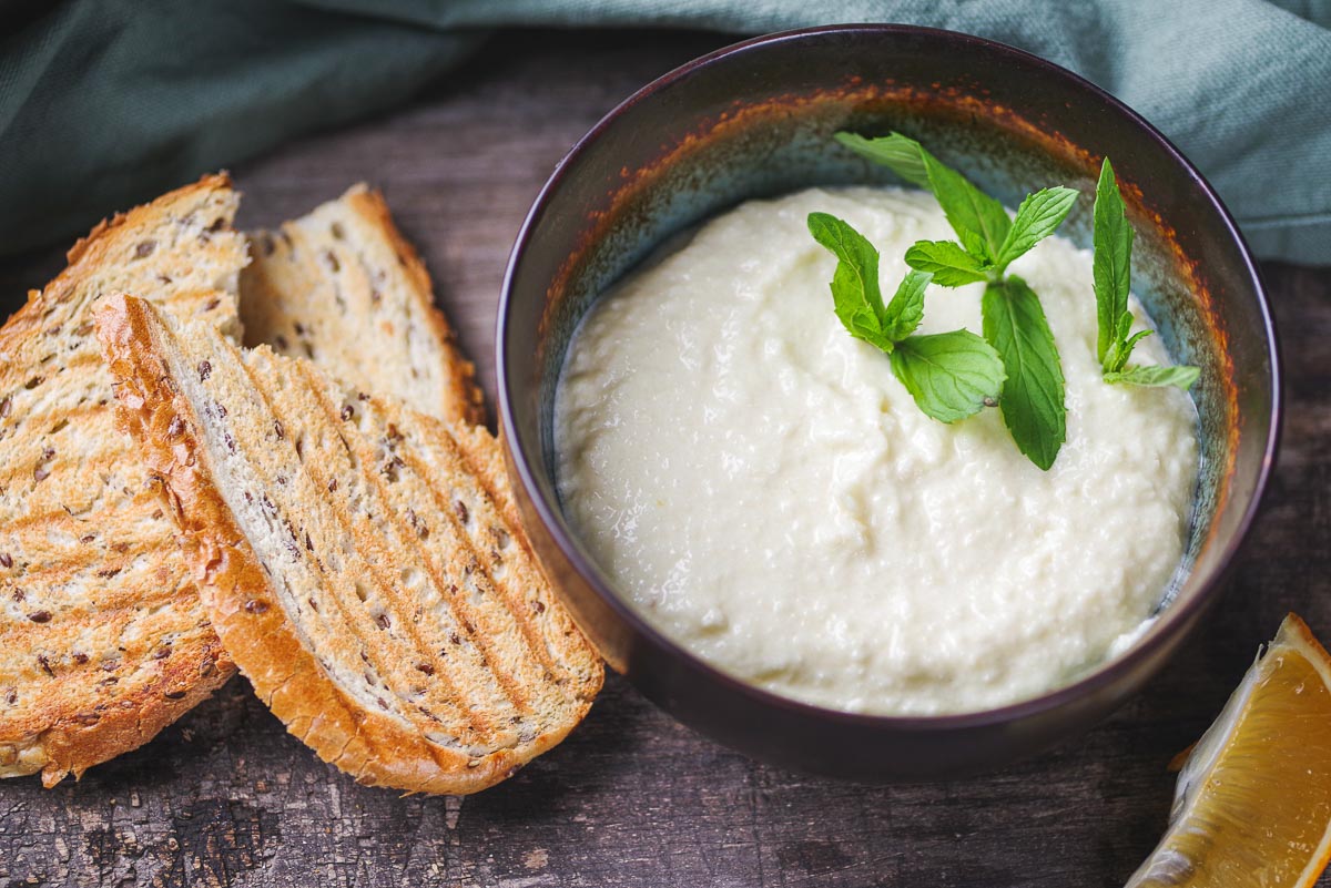 A bowl of Lebanese garlic sauce with bread next to it.