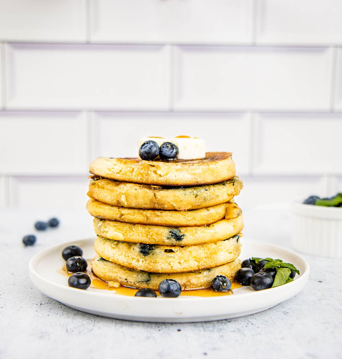 A tall stack of blueberry buttermilk pancakes with a pat of butter on top.