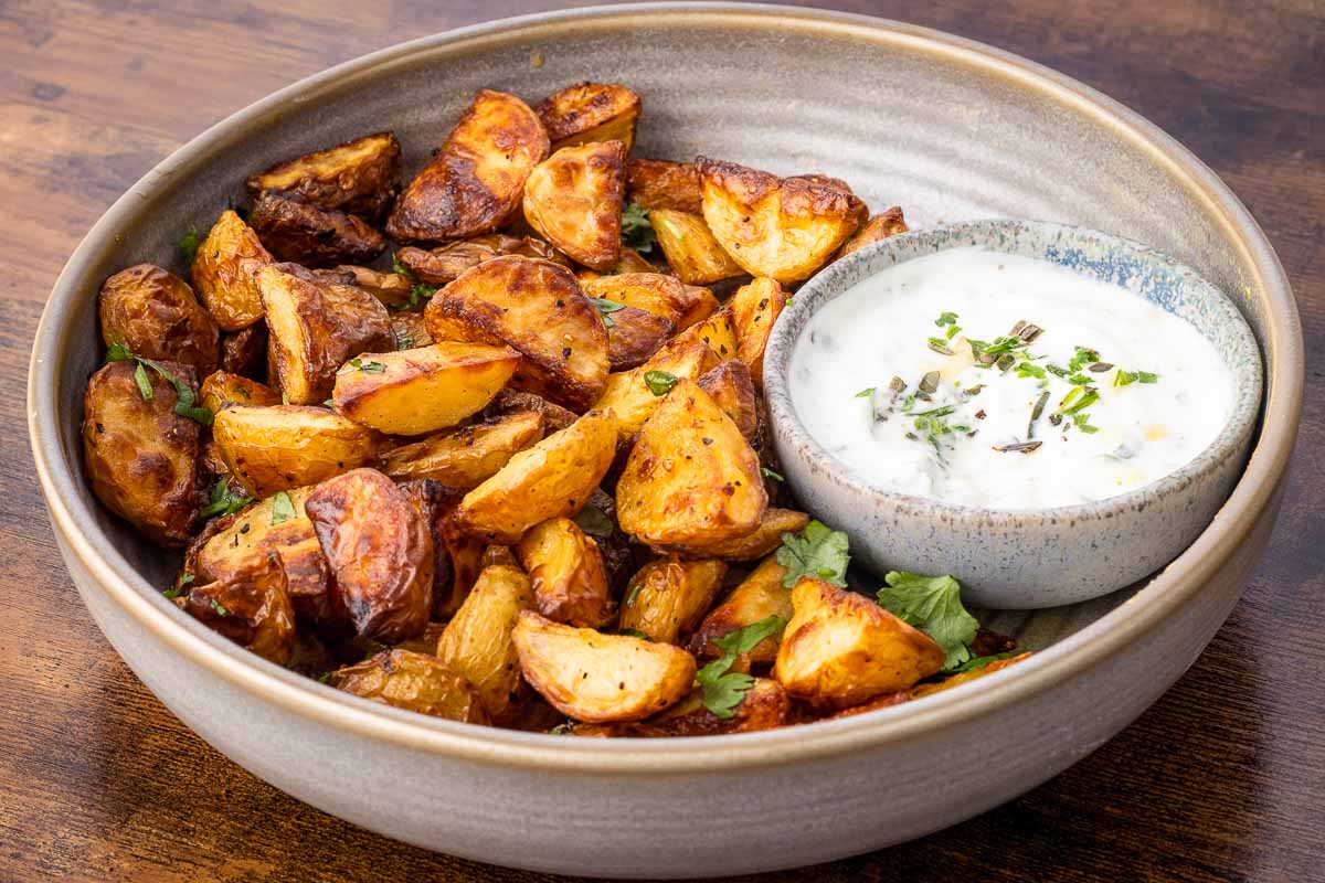 A bowl of herb and garlic breakfast potatoes served with garlic sauce.