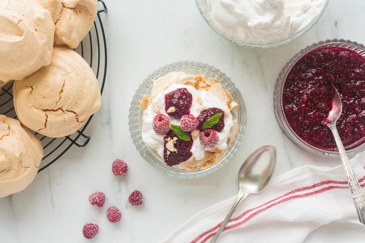 An Eton Mess made using brown meringues, topped with raspberries and whipped cream.