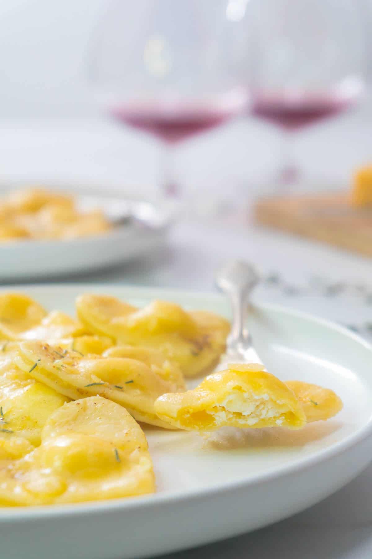 A ravioli piece that has been bitten into, revealing the cheese filling within.