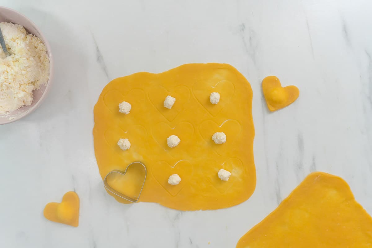 Heart-shaped ravioli in the process of being stuff with cheese.