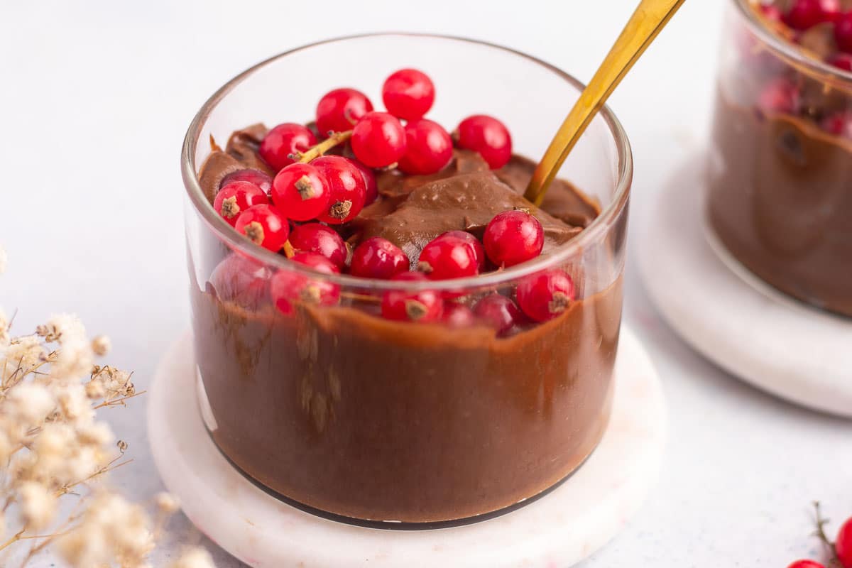 Vegan chocolate mousse in a glass, decorated with some berries.