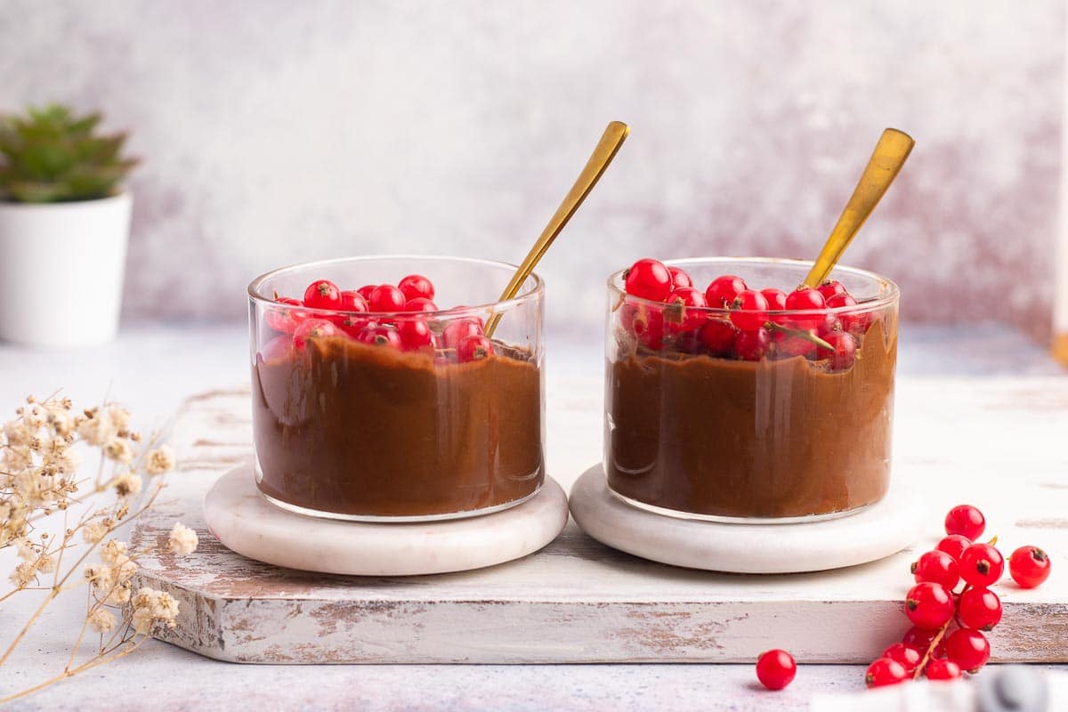 Two servings of vegan chocolate mousse next to each other on a table.