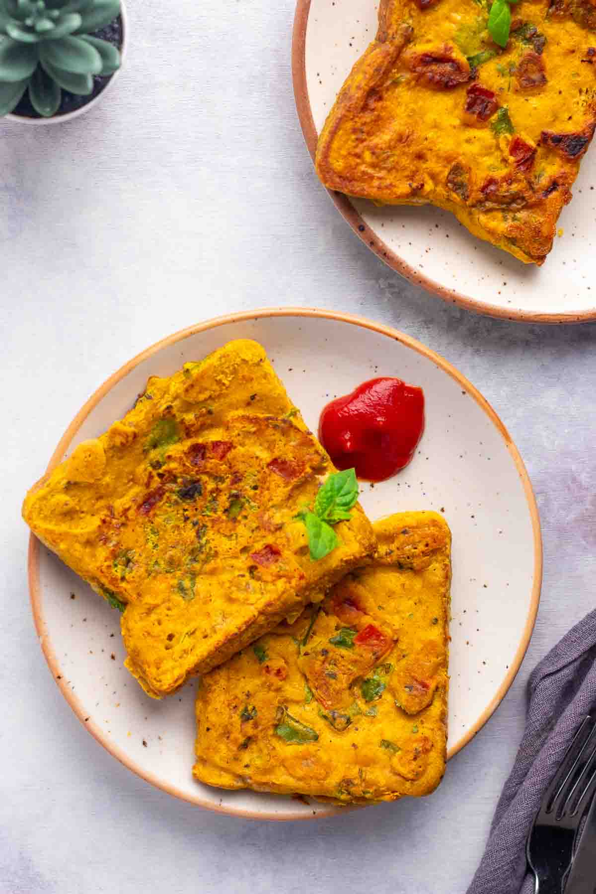 Masala toast on a plate with some tomato sauce.